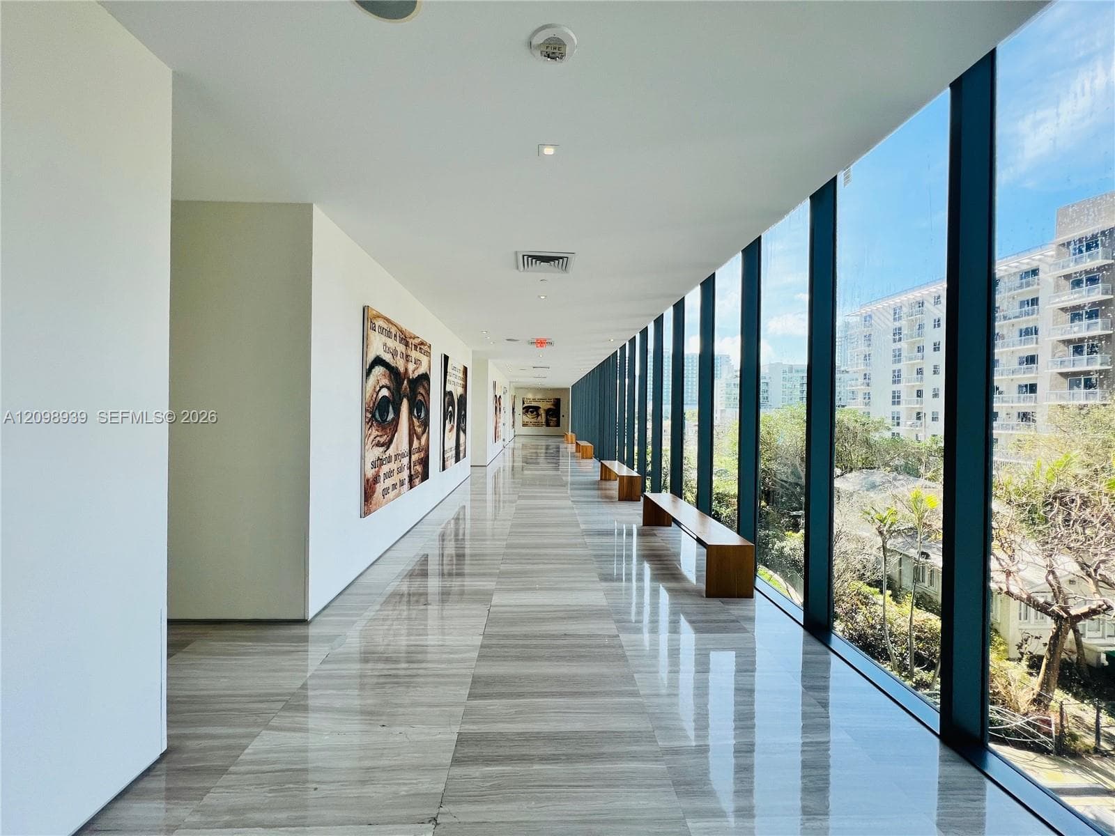 Expansive hallway featuring floor-to-ceiling windows, recessed lighting, and polished stone flooring