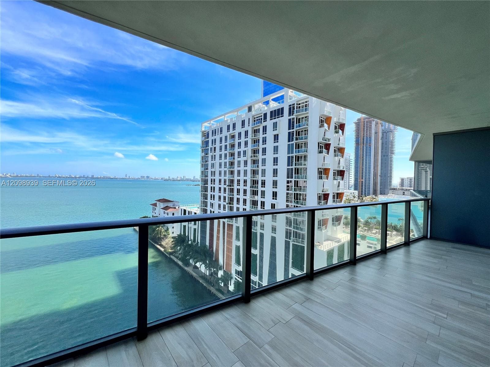 Balcony featuring a glass railing, water views, and wood-finish flooring