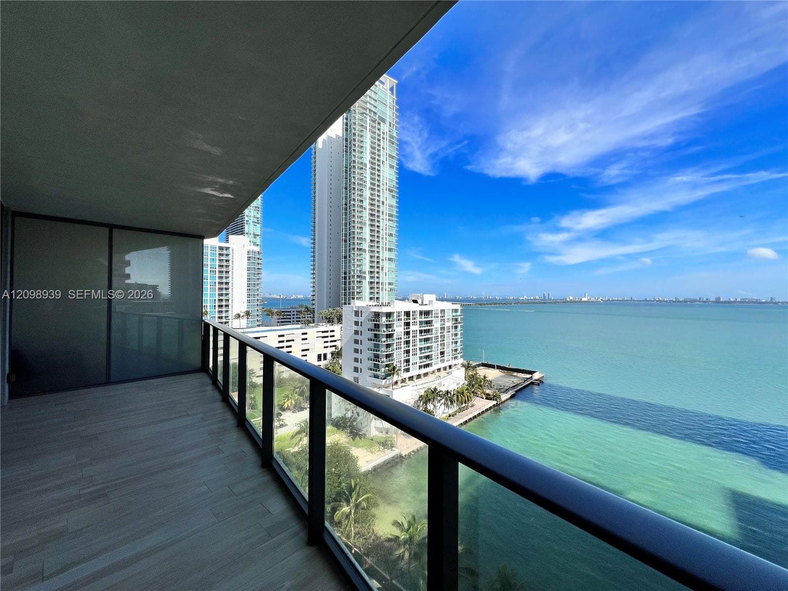 Balcony with wood-finish flooring, glass railing, and water scenery