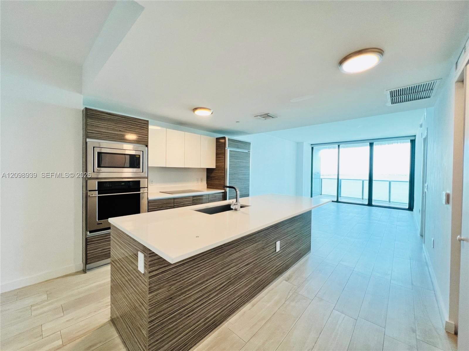 Modern kitchen with wood-finish cabinetry, stainless steel appliances, and a central island with an integrated sink
