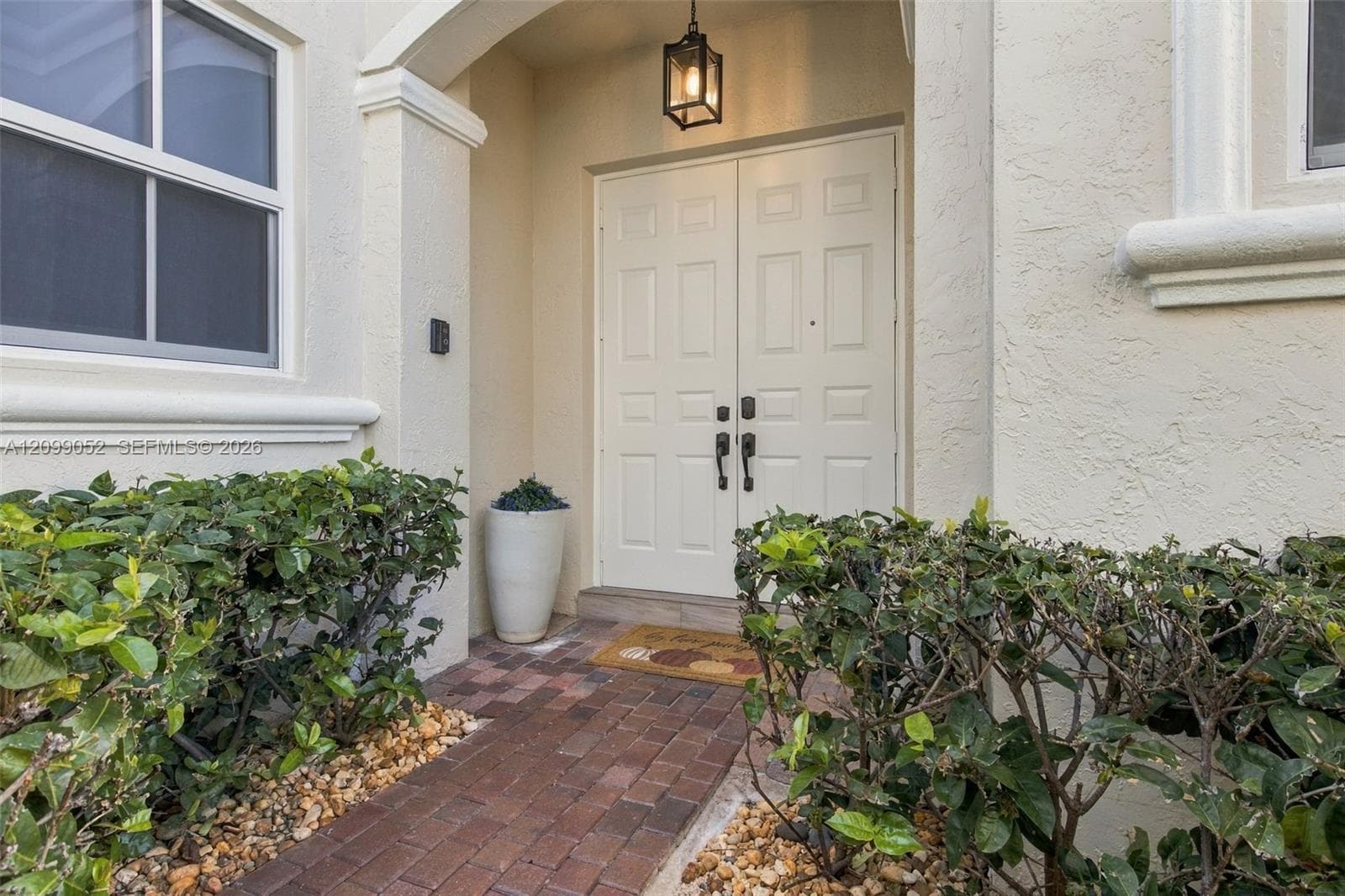 Covered entryway with a brick-paver walkway, double-door entrance, and overhead lantern-style lighting
