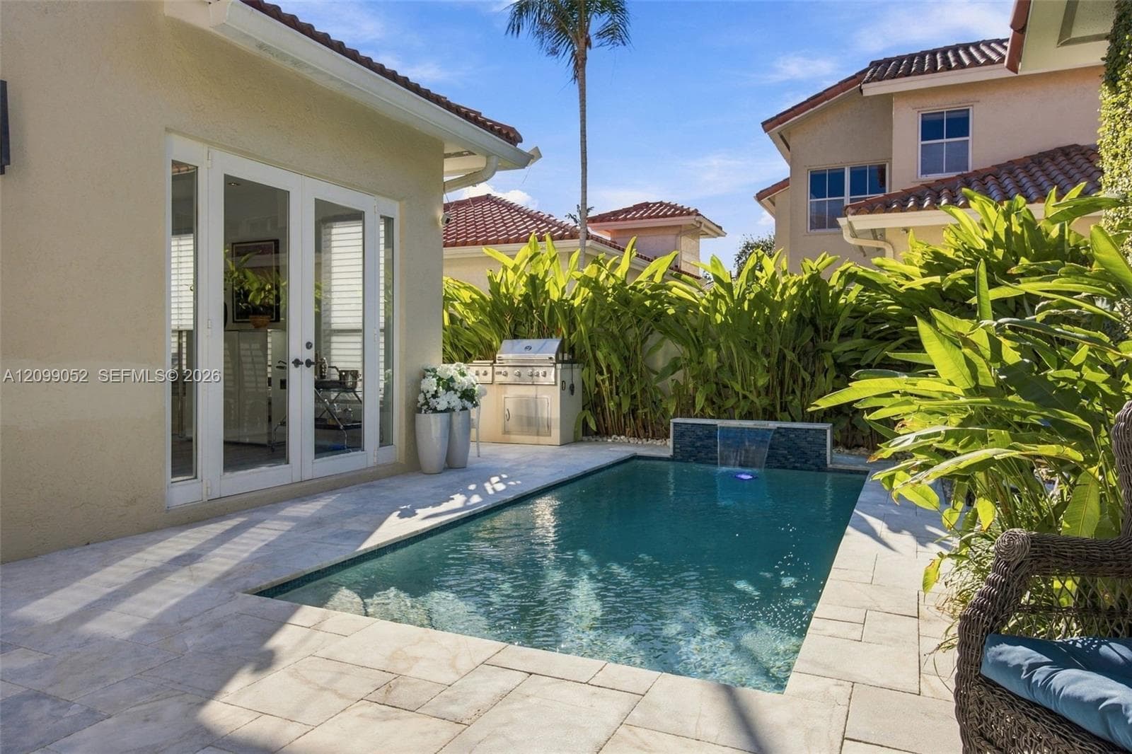 Backyard featuring an in-ground swimming pool with a tiled water feature, stone-paver decking, and a built-in outdoor grill station