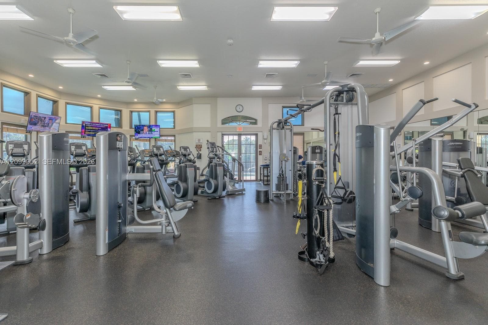 Fitness center featuring rubber flooring, recessed ceiling lighting, multiple ceiling fans, and an array of weight training and cardio equipment