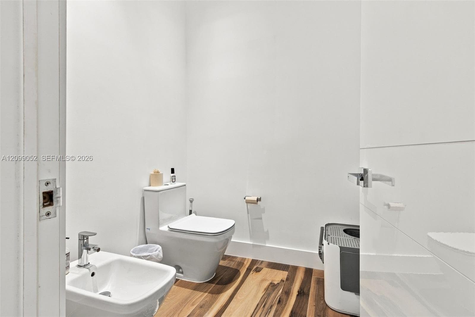 Bathroom featuring wood-finish flooring, a wall-mounted bidet with a chrome faucet, and a dual-flush toilet