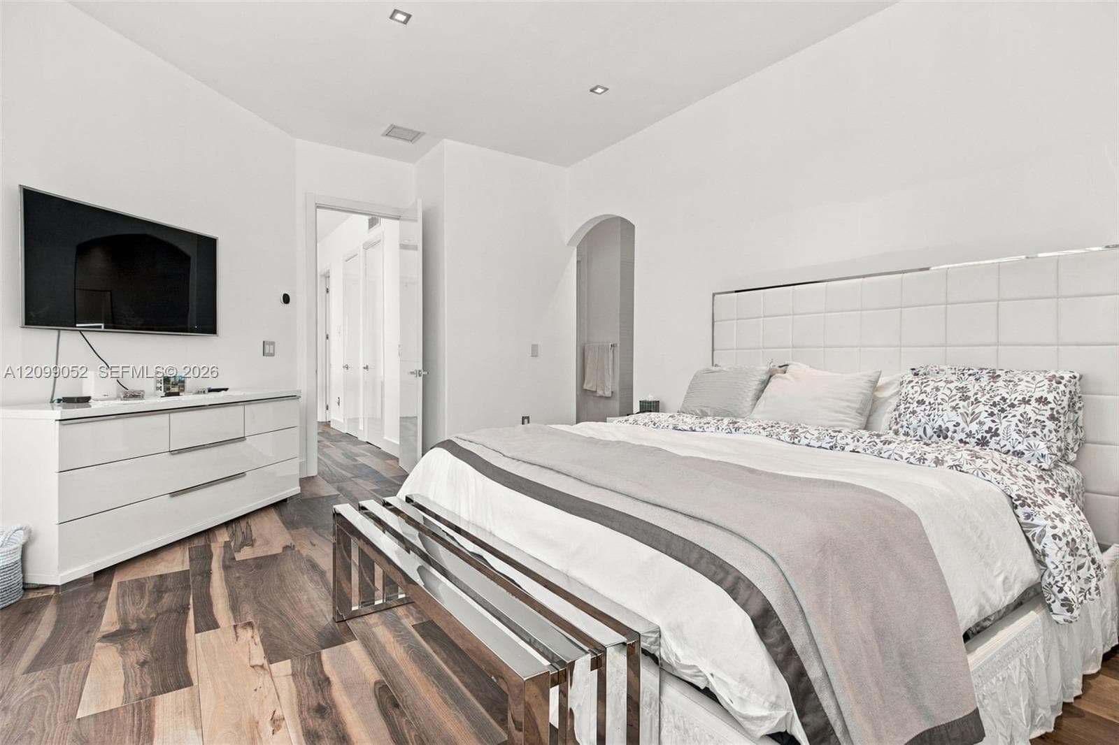Room interior featuring wood-finish flooring, recessed lighting, and an arched doorway