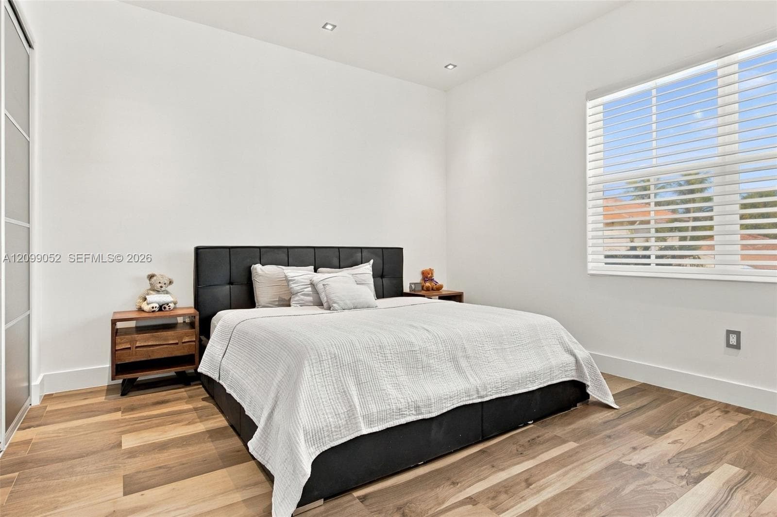 Bedroom featuring wood-finish flooring, recessed lighting, and a window with horizontal blinds