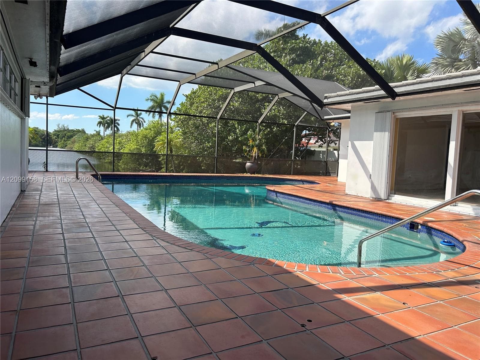 Screened-in pool area featuring terracotta-style tile decking, a metal-framed enclosure, and integrated handrails
