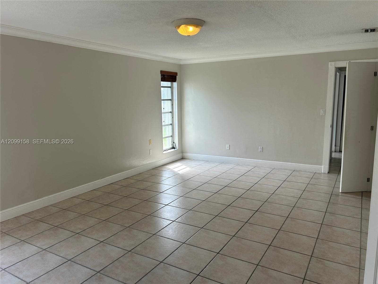 Interior space featuring neutral wall paint, tile flooring, crown molding, and a flush-mount ceiling light fixture