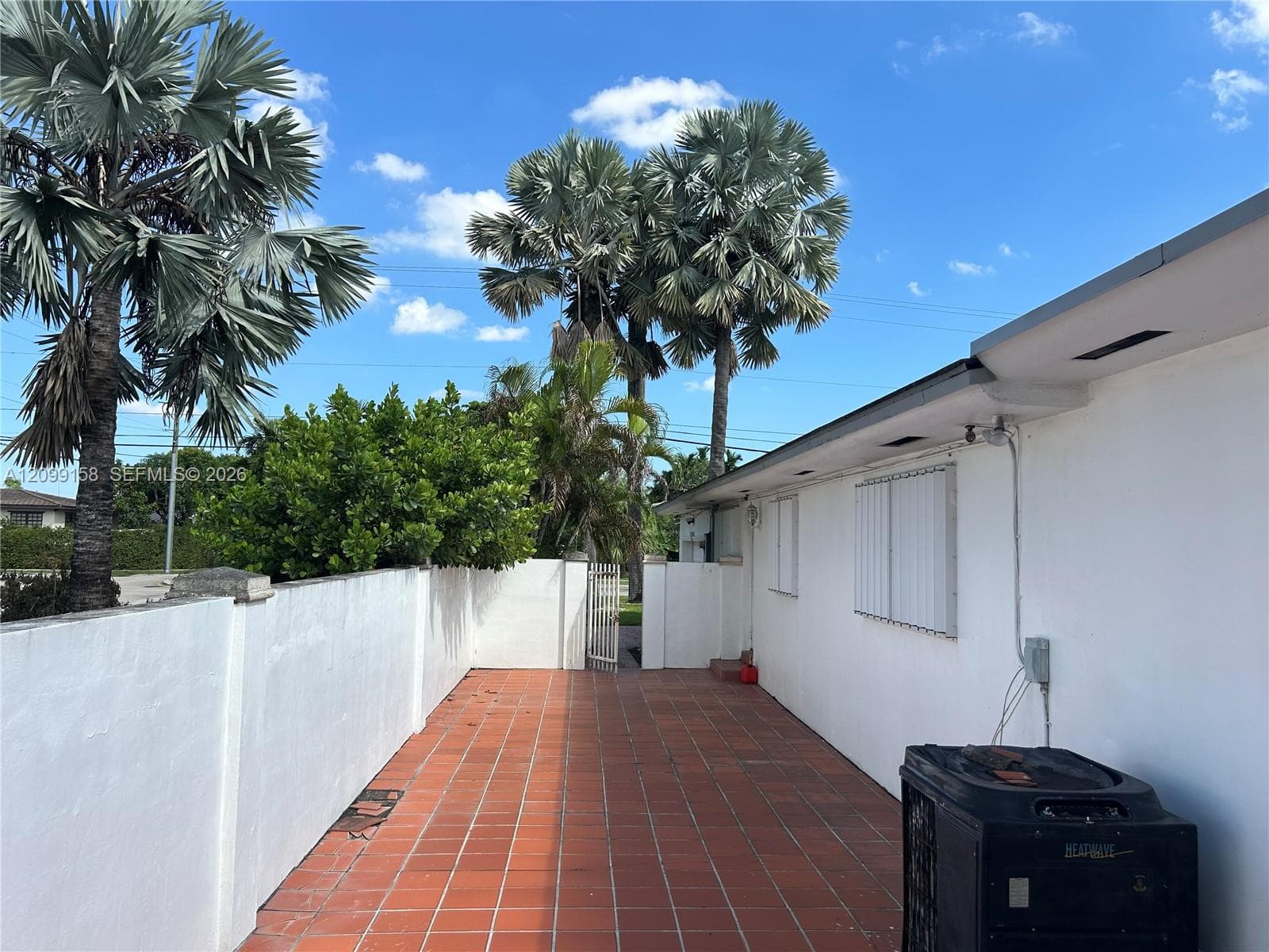 Private exterior courtyard featuring terracotta tile flooring, smooth stucco wall enclosure, and integrated metal gate