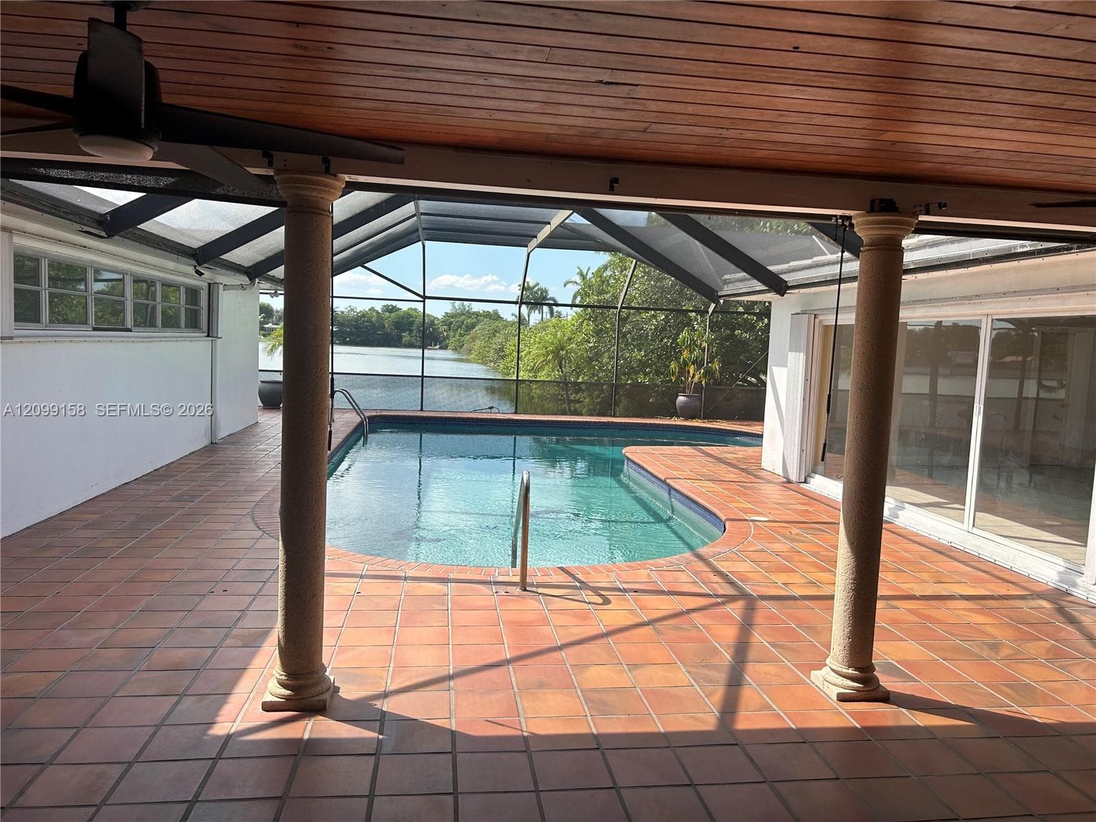 Covered patio featuring a wood-plank ceiling, structural columns, tile flooring, and a screened enclosure surrounding the swimming pool