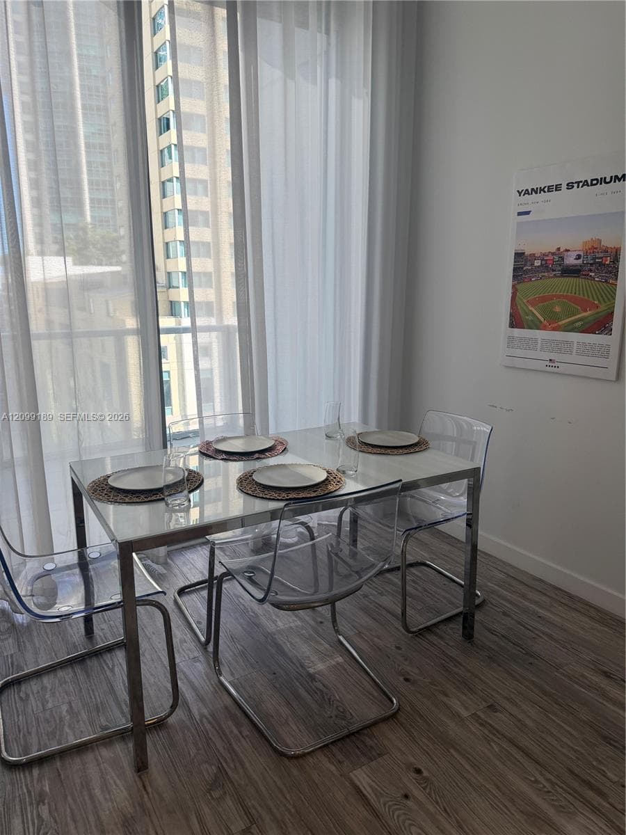 Floor-to-ceiling windows with sheer drapery, wood-finish flooring, and neutral wall tones
