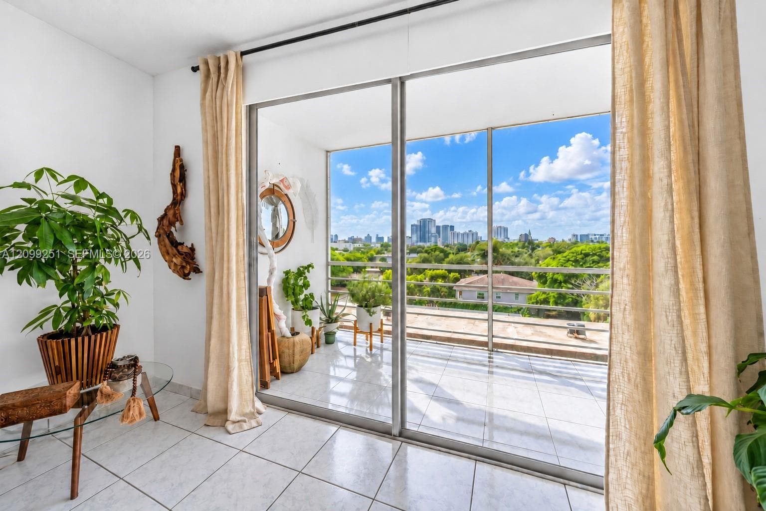 Sliding glass doors opening to a balcony with tile flooring and a distant cityscape