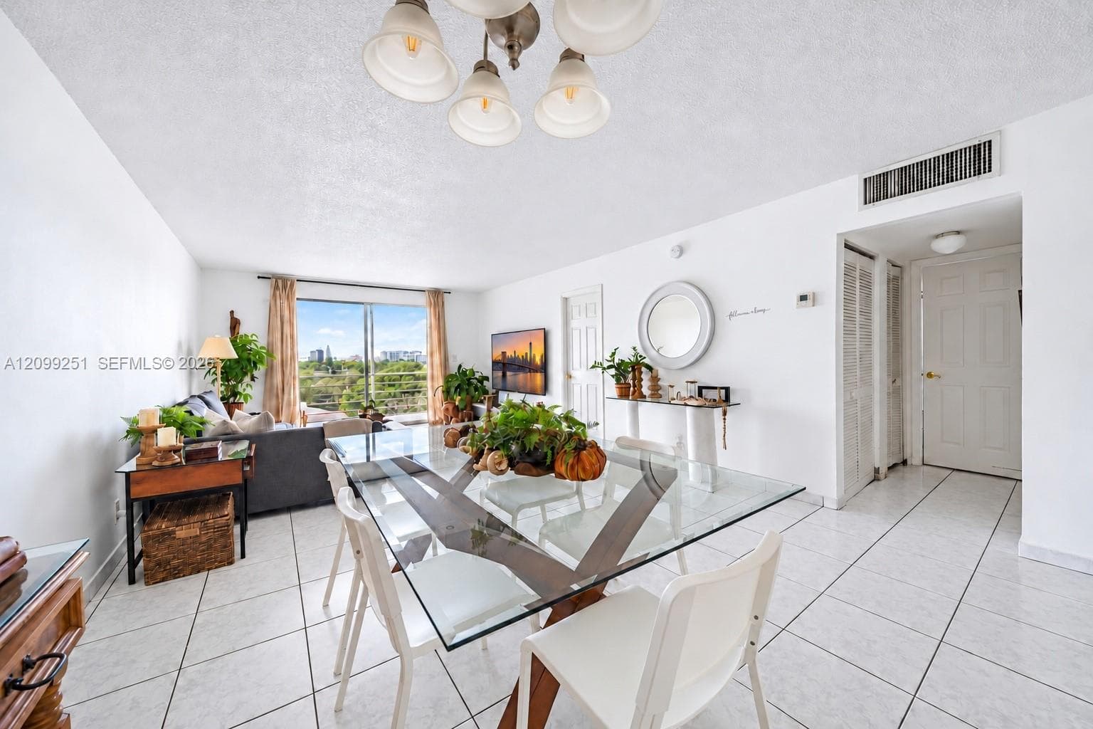 Open-concept living area with white tile flooring and a glass dining table