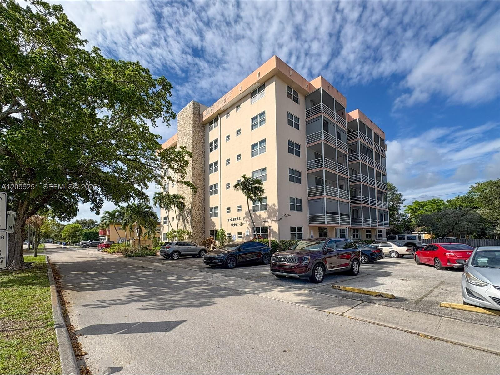 Multi-story residential building featuring a stucco exterior with stone accents and multiple screened balconies