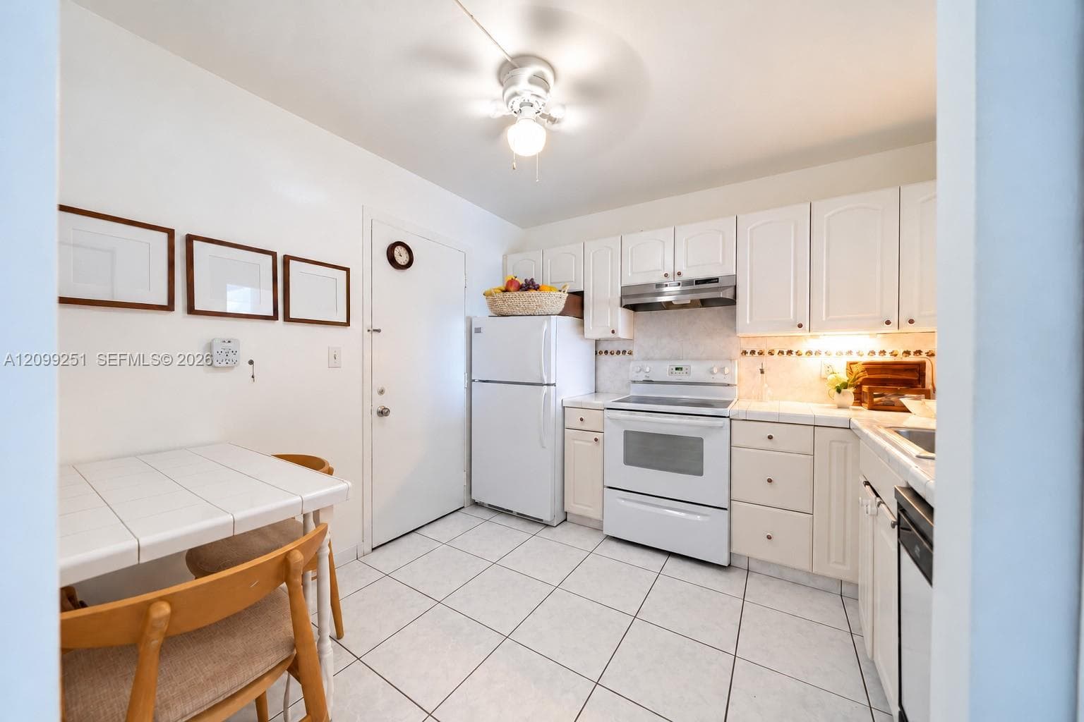 White tile flooring, white cabinetry, white electric range with overhead range hood, white refrigerator, and a built-in dishwasher