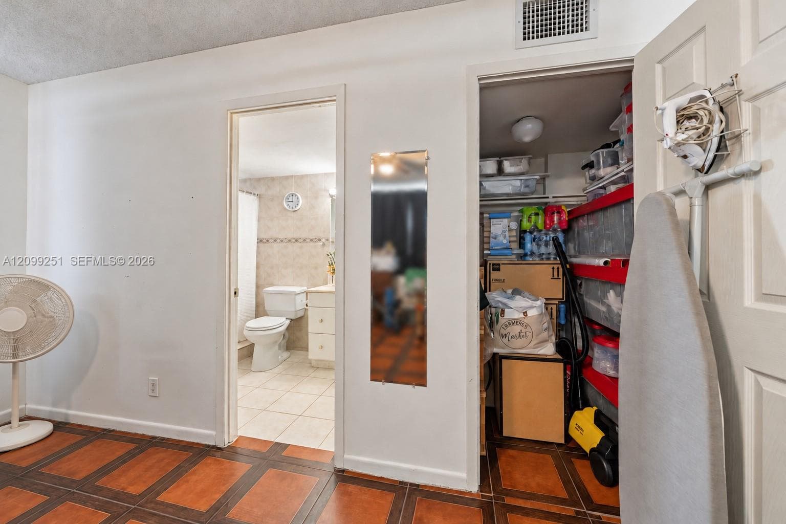 Tiled flooring with wood-finish accents, white walls, and a recessed ceiling vent