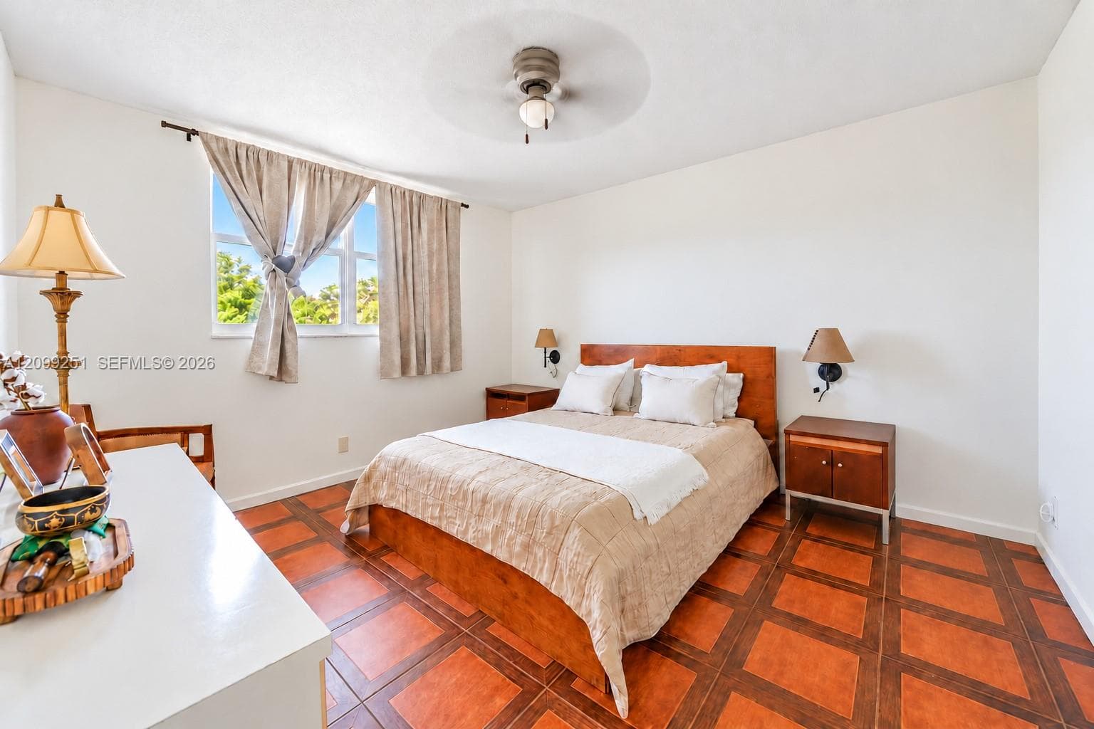 White walls, patterned tile flooring, a window with natural light, and a ceiling fan with integrated lighting