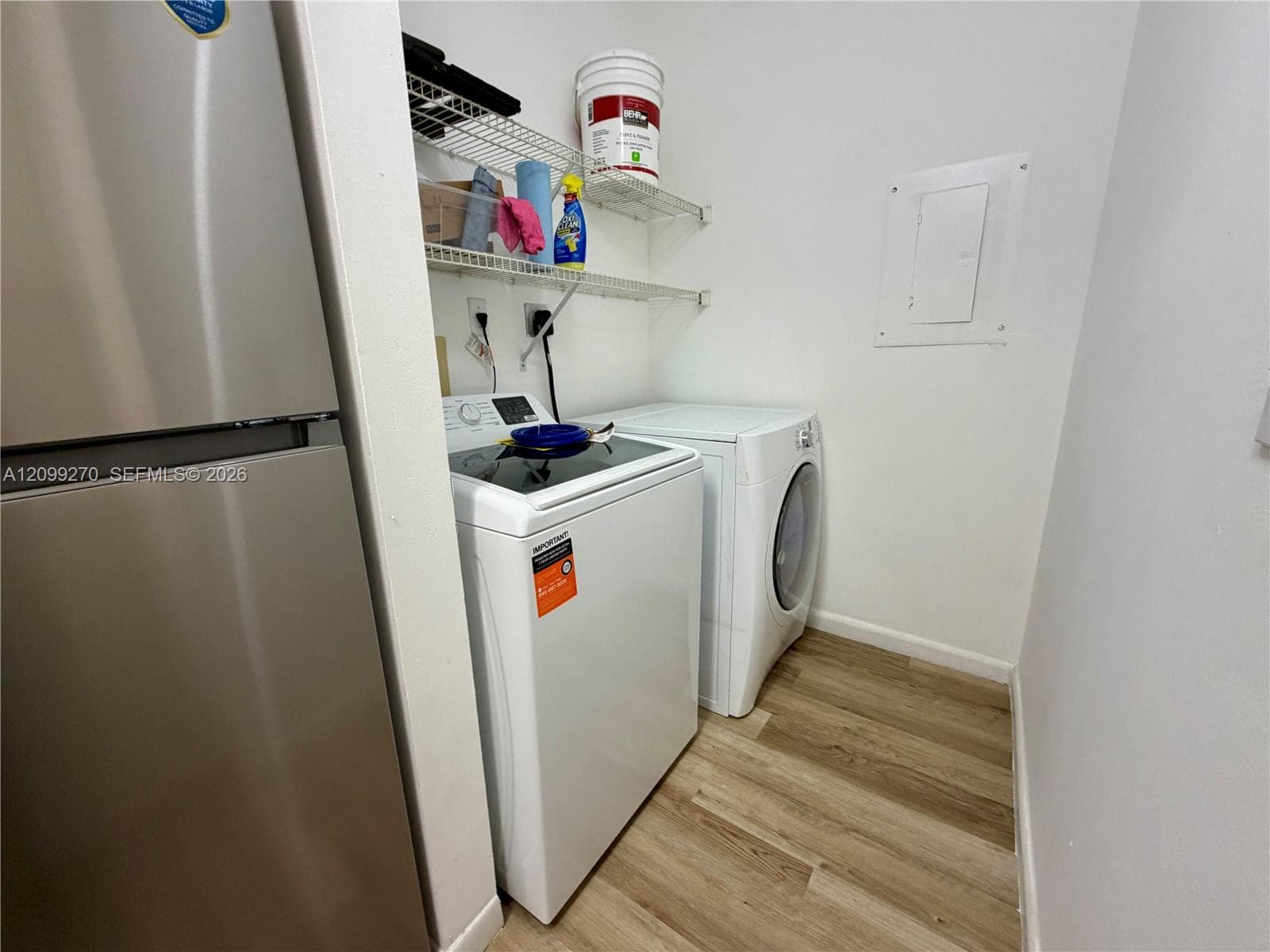 Dedicated laundry alcove featuring wood-finish flooring and integrated wire shelving