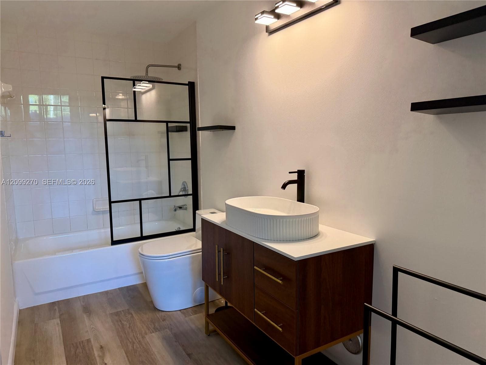 Modern bathroom featuring a floating dark wood vanity with a white vessel sink, matte black wall-mounted faucet, and quartz countertop