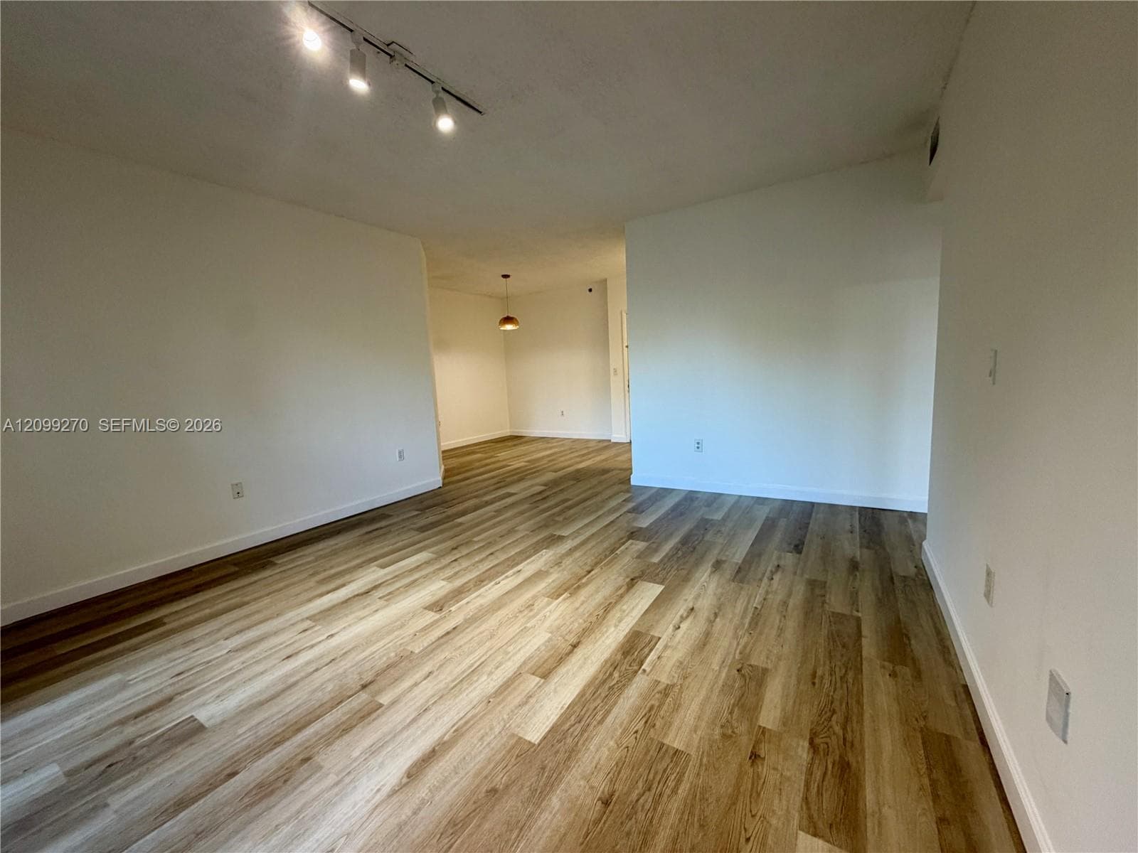 Interior space featuring wood-finish flooring, ceiling-mounted track lighting, and neutral wall paint