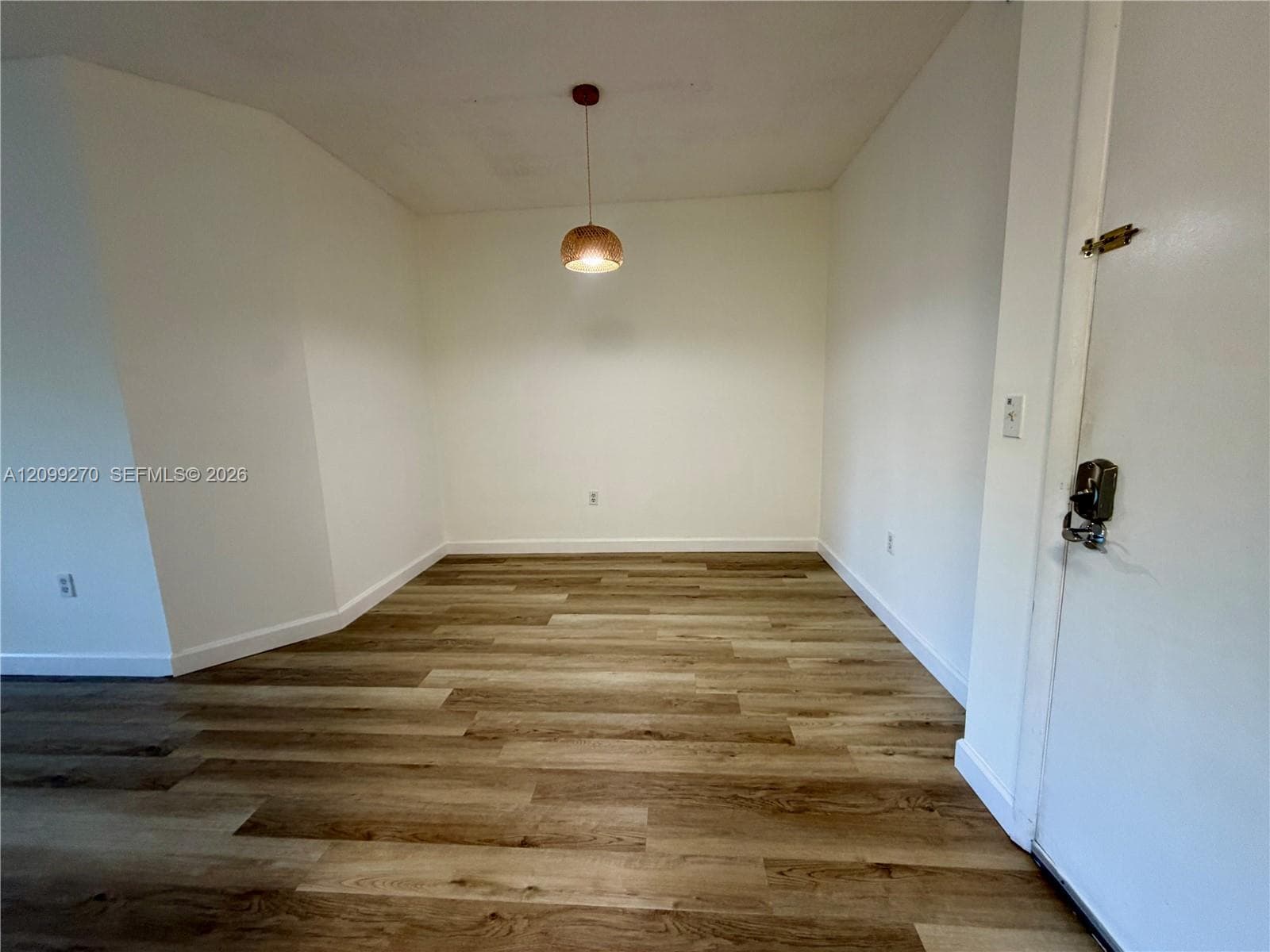 Interior space featuring wood-finish flooring, white walls, and a pendant light fixture
