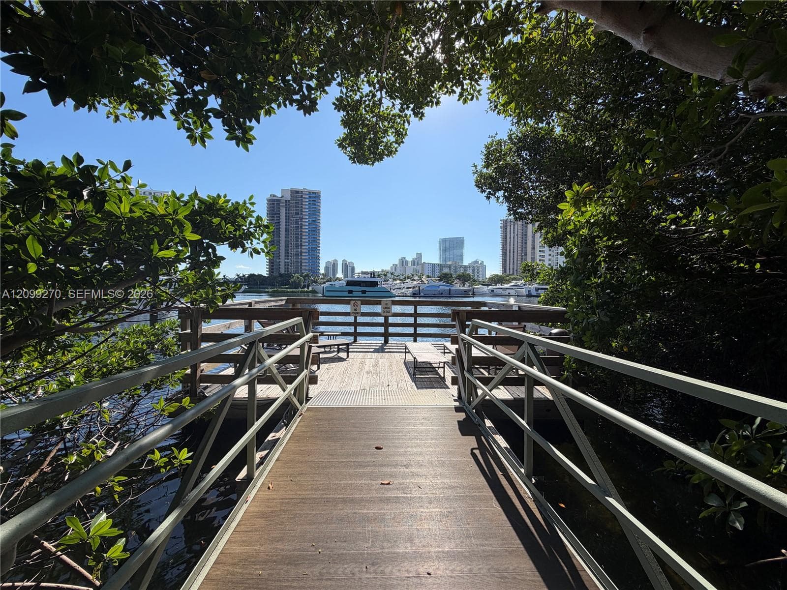 Waterfront dock featuring wooden decking, metal railings, and a pedestrian ramp