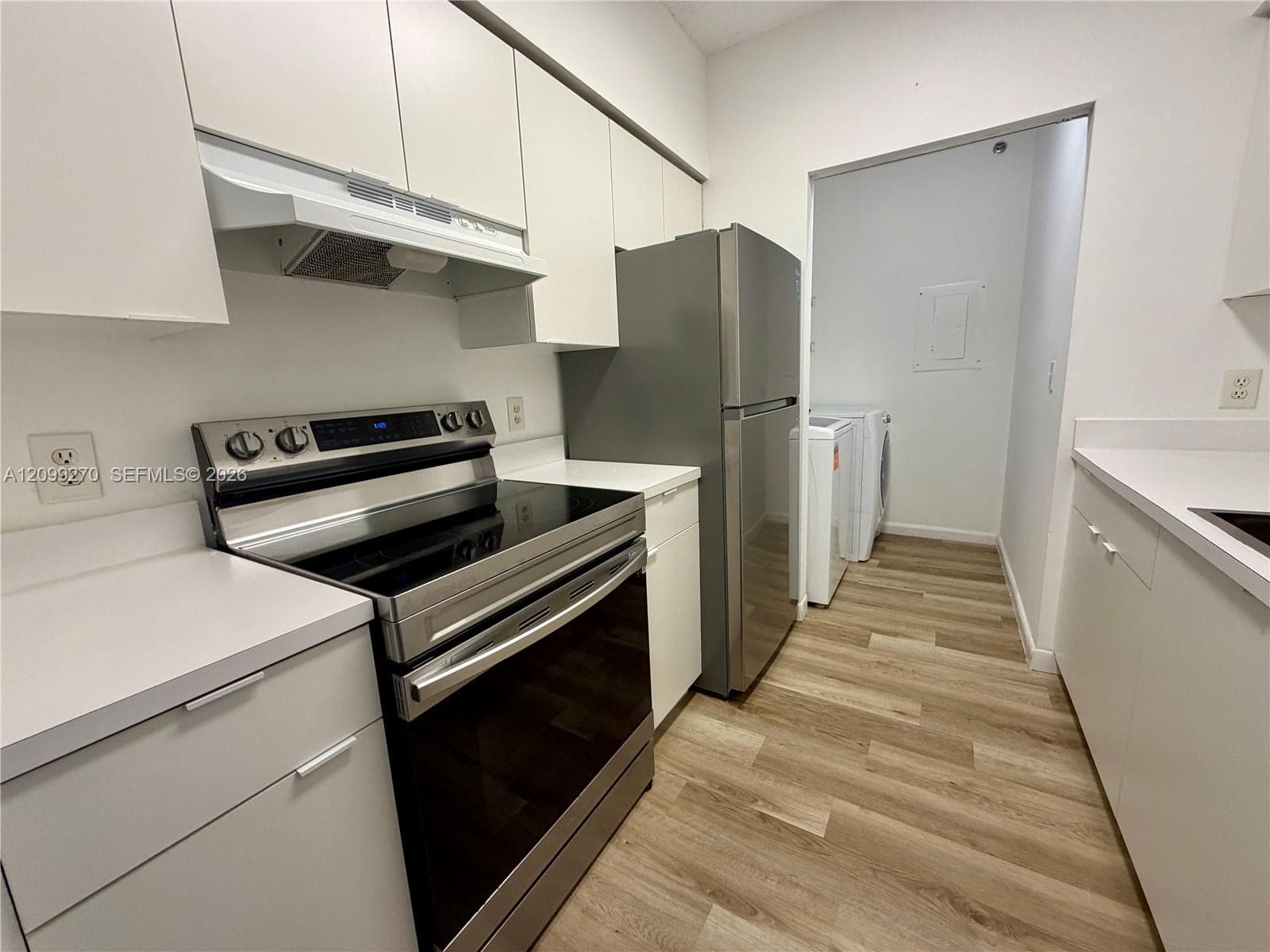 Kitchen featuring white cabinetry, solid-surface countertops, stainless steel appliances, and wood-finish flooring