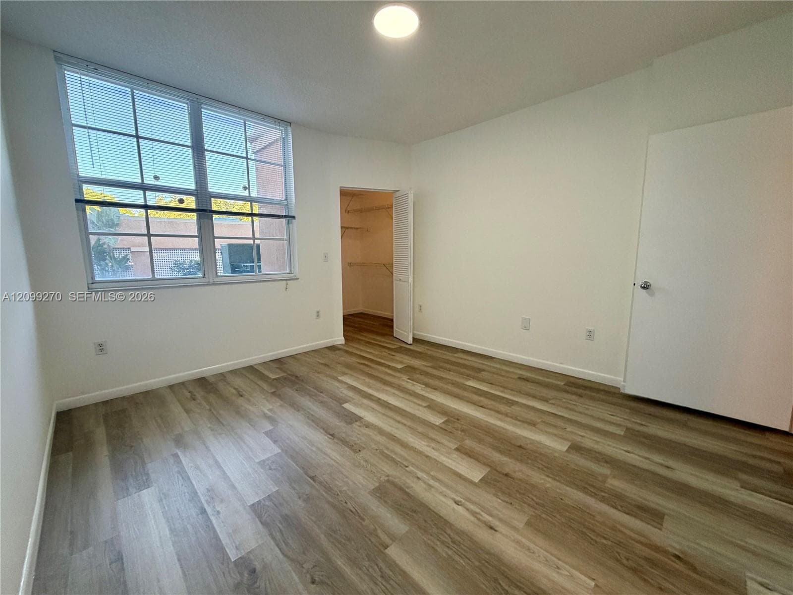 Wood-finish flooring, multi-pane window with natural light, and walk-in closet with built-in shelving