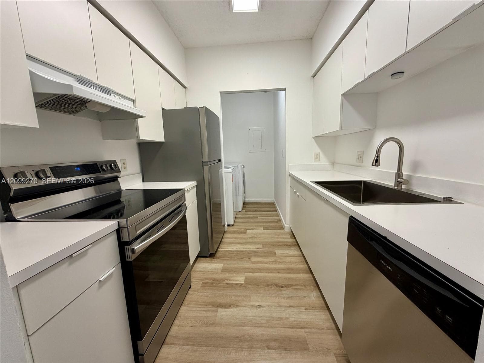 Kitchen featuring white flat-panel cabinetry, stainless steel appliances, solid surface countertops, a gooseneck faucet, and wood-finish flooring