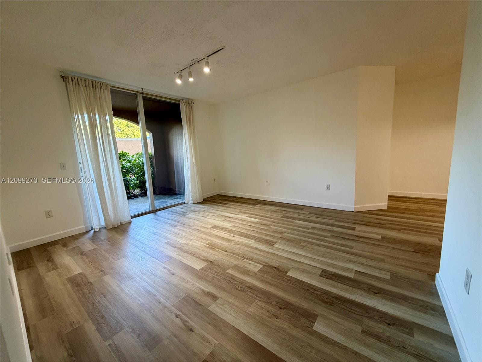 Wood-finish flooring, recessed track lighting, and a sliding glass door providing access to an exterior patio