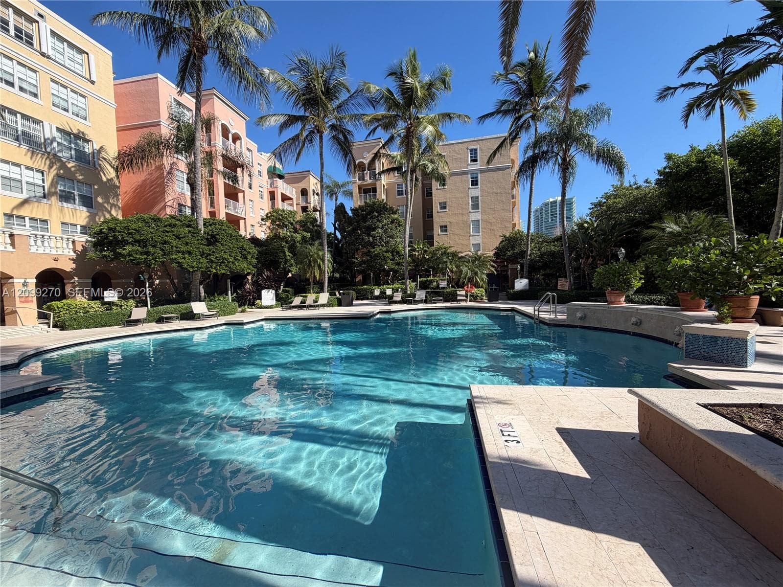 Swimming pool featuring stone decking, perimeter landscaping with mature palms, and built-in masonry planters