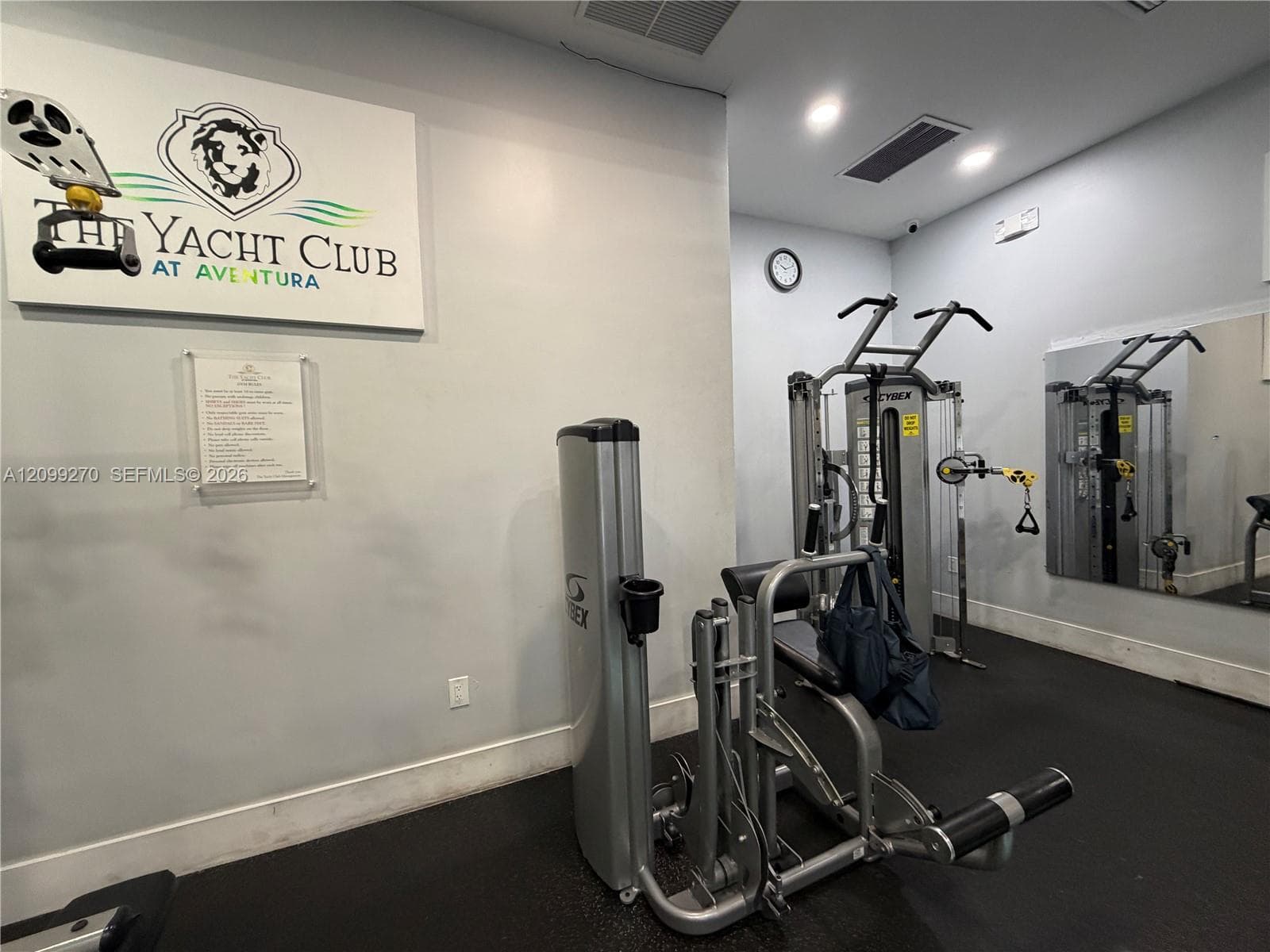 Fitness facility featuring rubberized flooring, mirrored walls, and mounted multi-station exercise equipment