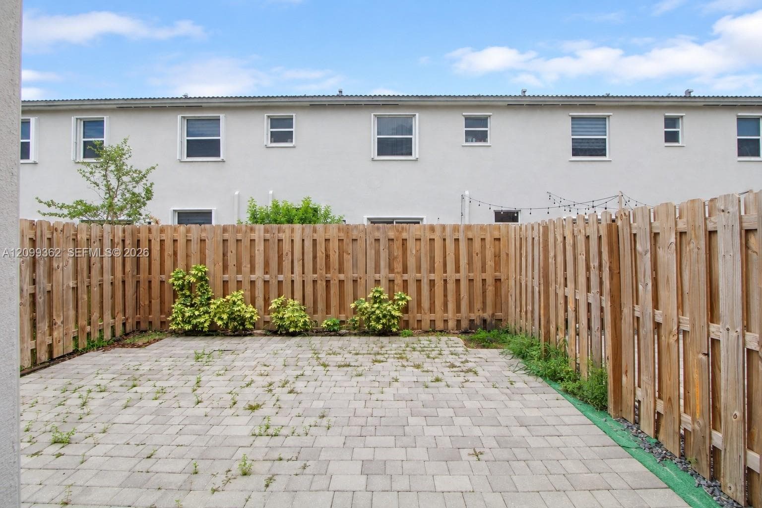 Private backyard area featuring a paved stone patio, perimeter wood fencing, and low-maintenance landscaping