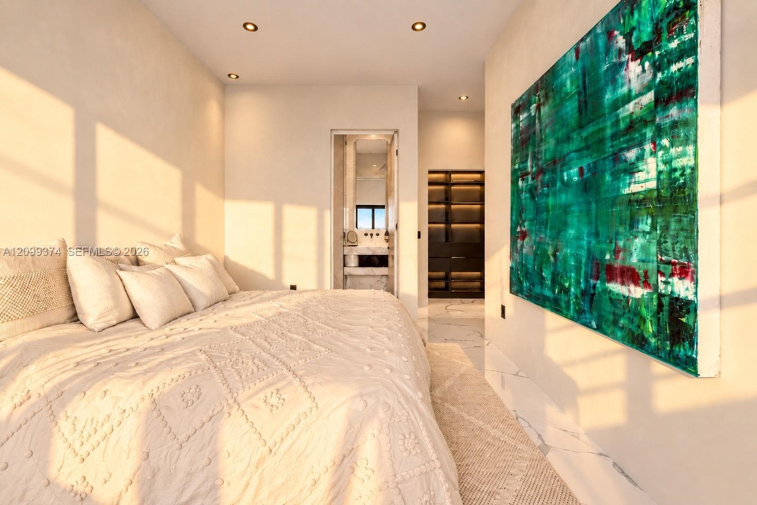 Bedroom illuminated by golden-hour light with statement art