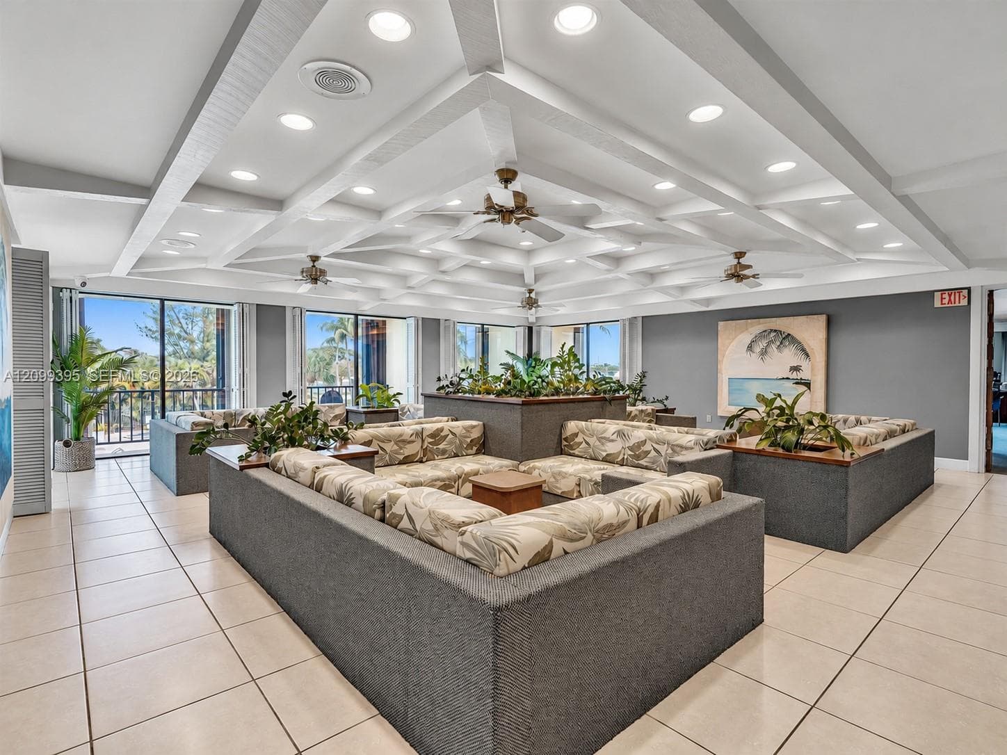 Expansive common area featuring a coffered ceiling, recessed lighting, ceiling fans, tile flooring, and large glass sliding doors