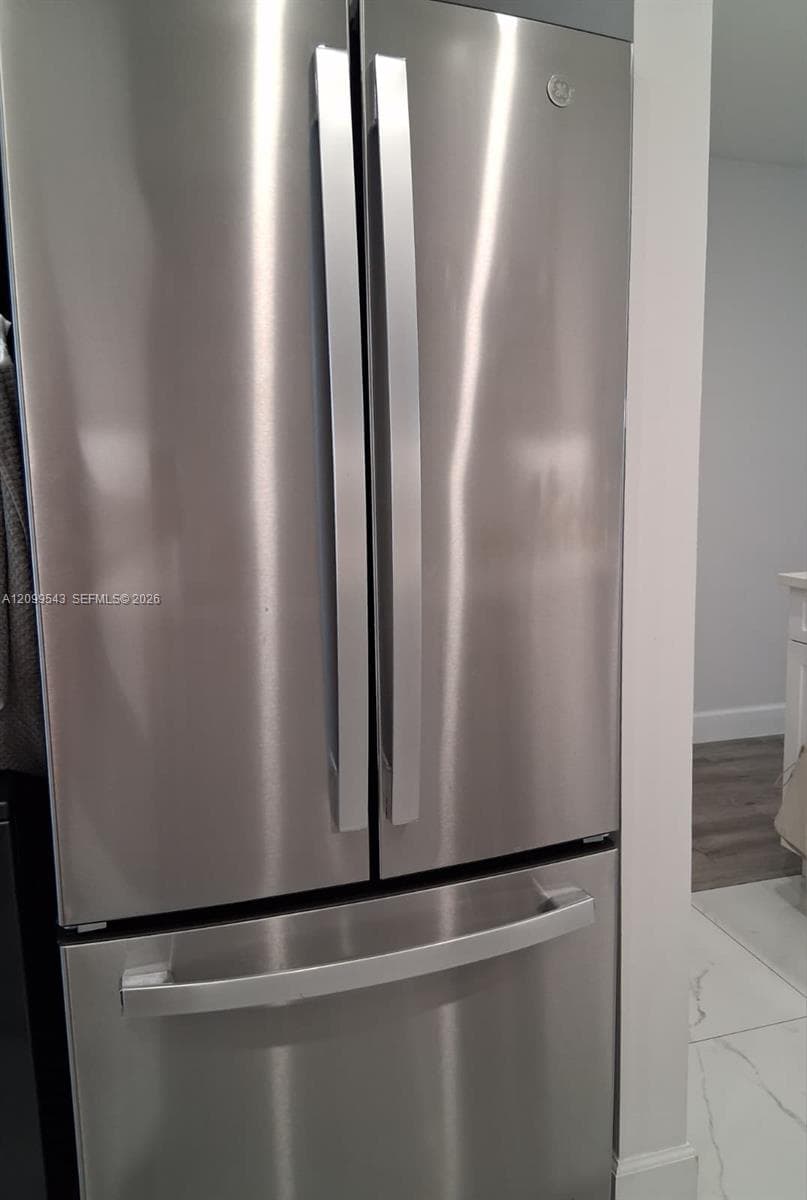 Stainless steel French door refrigerator with a bottom-mount freezer drawer and integrated handles