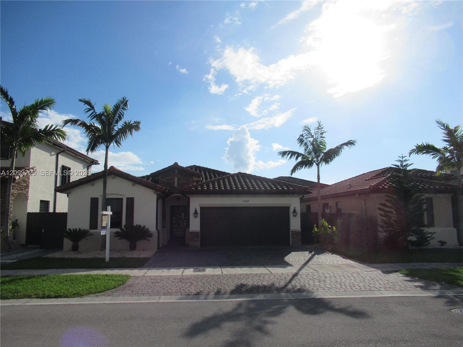 Single-story residence featuring a tile roof, stucco exterior, attached two-car garage, and a paver driveway