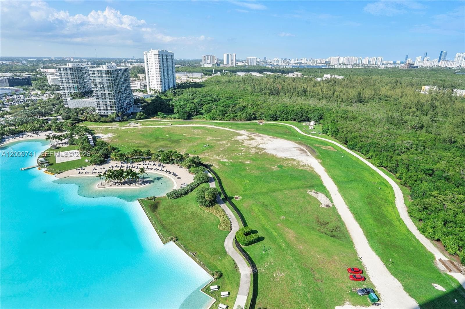 Expansive waterfront parcel featuring a man-made lagoon, paved walking paths, manicured green space, and mature perimeter landscaping