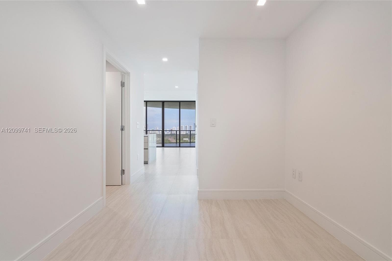 Neutral-toned tile flooring, recessed ceiling lighting, and floor-to-ceiling dark-framed glass paneling