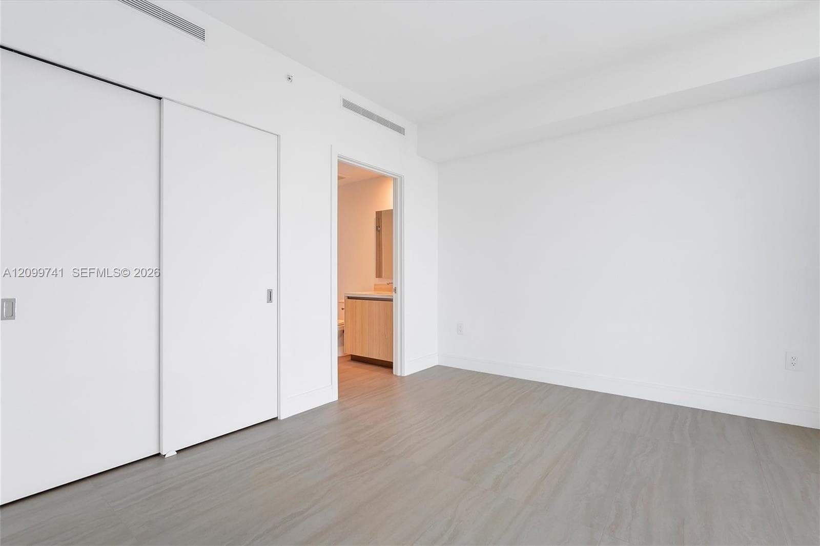 Neutral-toned wood-finish flooring, white sliding-door closet, and overhead recessed HVAC integration