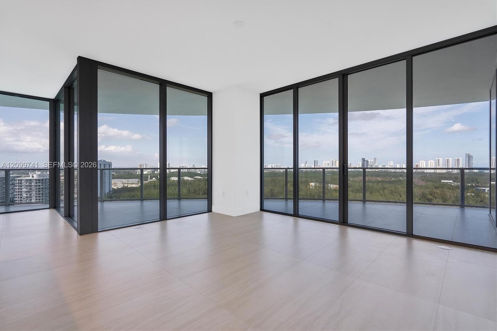 Floor-to-ceiling glass walls, wrap-around balcony with metal railings, and wood-finish flooring