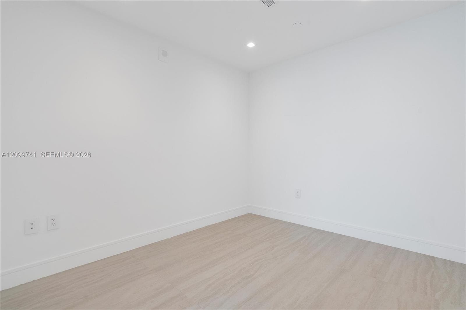 Neutral interior room featuring wood-finish flooring, recessed lighting, and wall-mounted electrical outlets