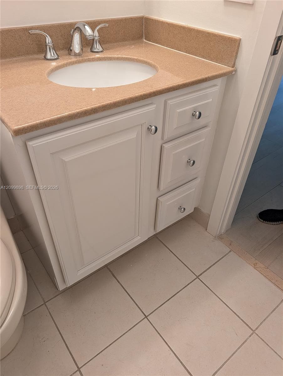 White vanity cabinet featuring three soft-close drawers and one door with chrome hardware, topped with a solid surface countertop, integrated sink, and dual-handle chrome faucet