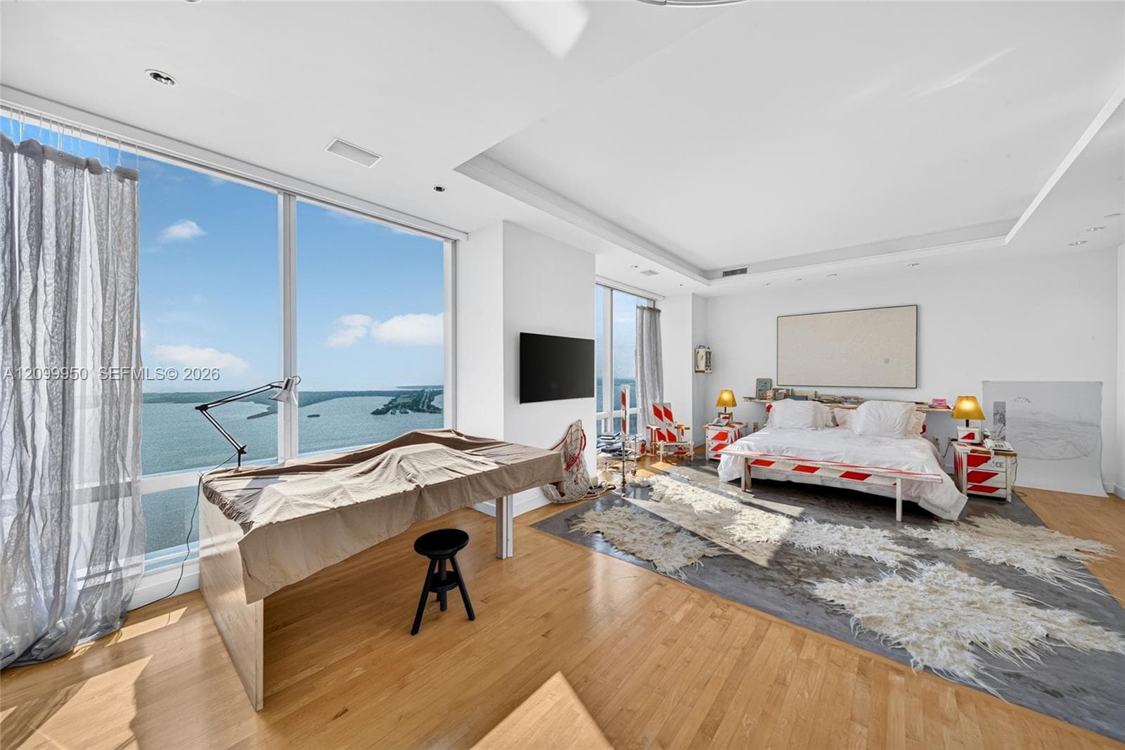 Floor-to-ceiling windows featuring panoramic water scenery, light-toned wood-finish flooring, recessed ceiling lighting, and crisp white wall finishes