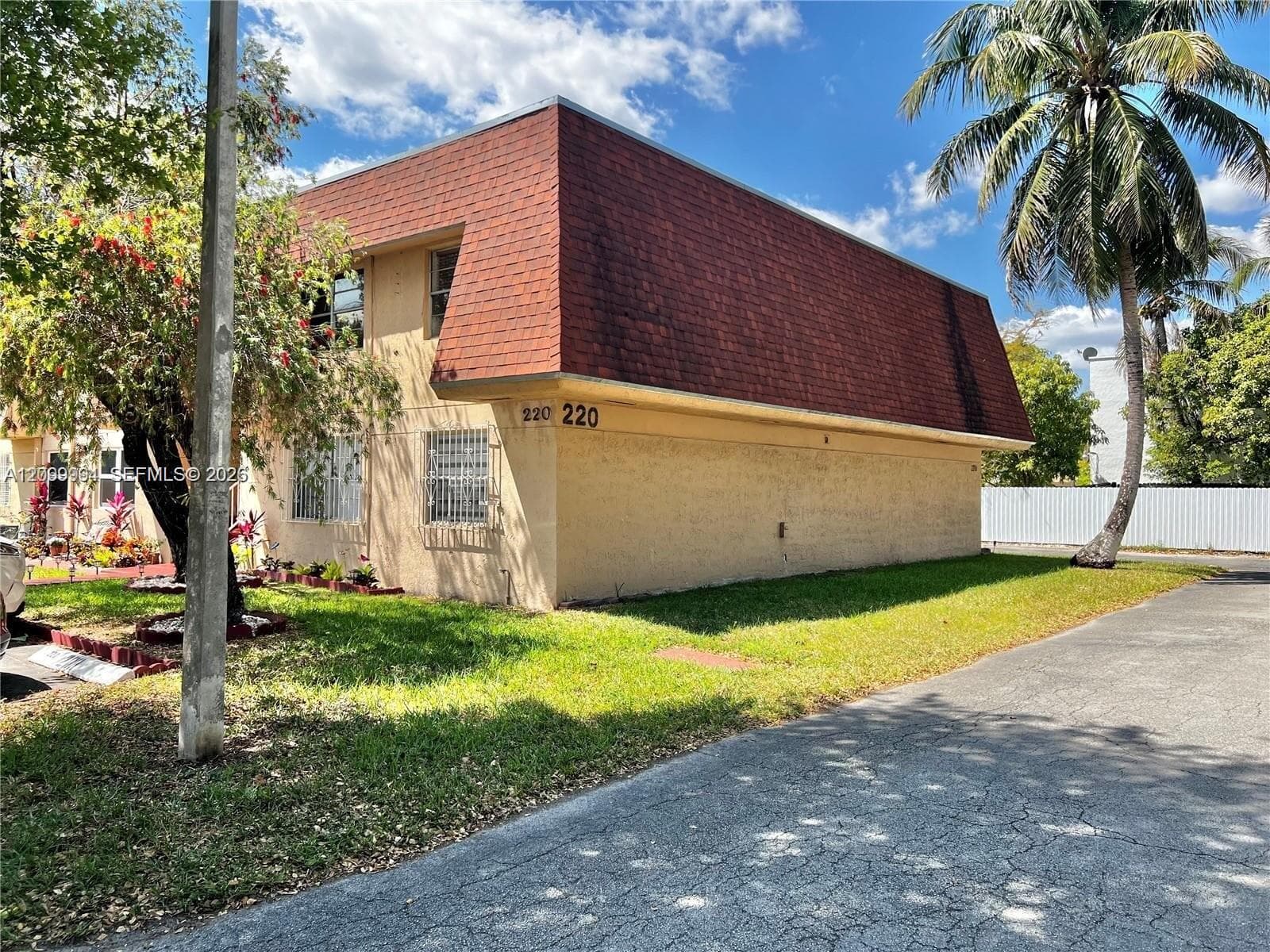 Property exterior featuring a red mansard roof, stucco finish, and a paved driveway