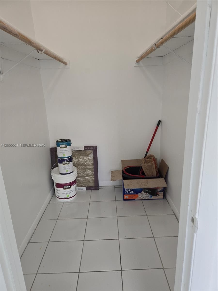 Storage closet featuring ceramic tile flooring, neutral walls, and dual built-in overhead shelves with hanging rods