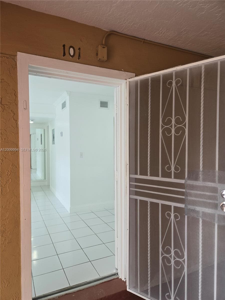 Perforated security screen door with decorative wrought iron accents