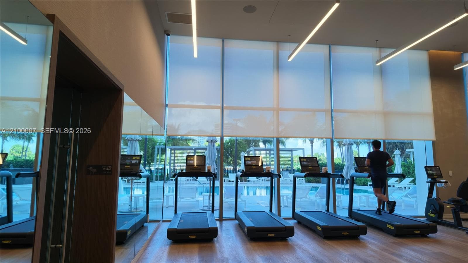 Wood-finish flooring with recessed ceiling lighting, textured wall finishes, and a contemporary light wood door