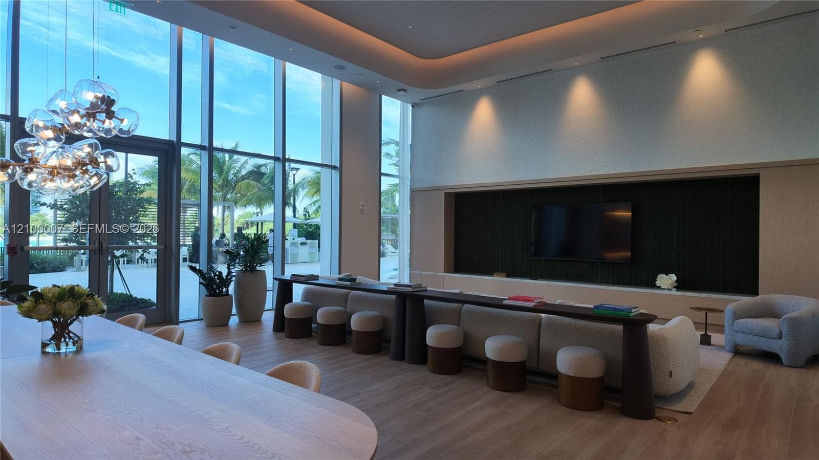 Wood-finish flooring, built-in cabinetry with stone countertop and backsplash, modern chandelier, built-in shelving with accent lighting, and a wood-panel door with glass inserts