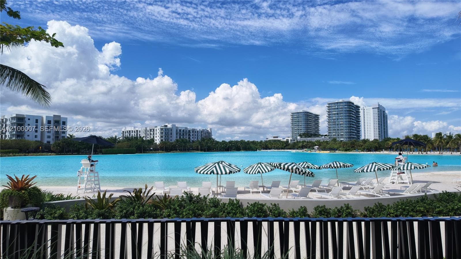 Expansive lagoon with pristine sand-edged shores, surrounded by lush landscaping and resort-style buildings
